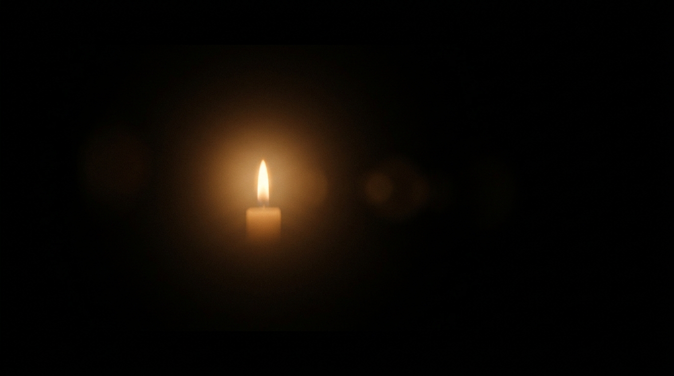 Eine einzelne kleine Kerzenflamme in völliger Dunkelheit.